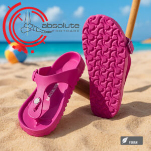 Pink vegan sandals on a sandy beach.